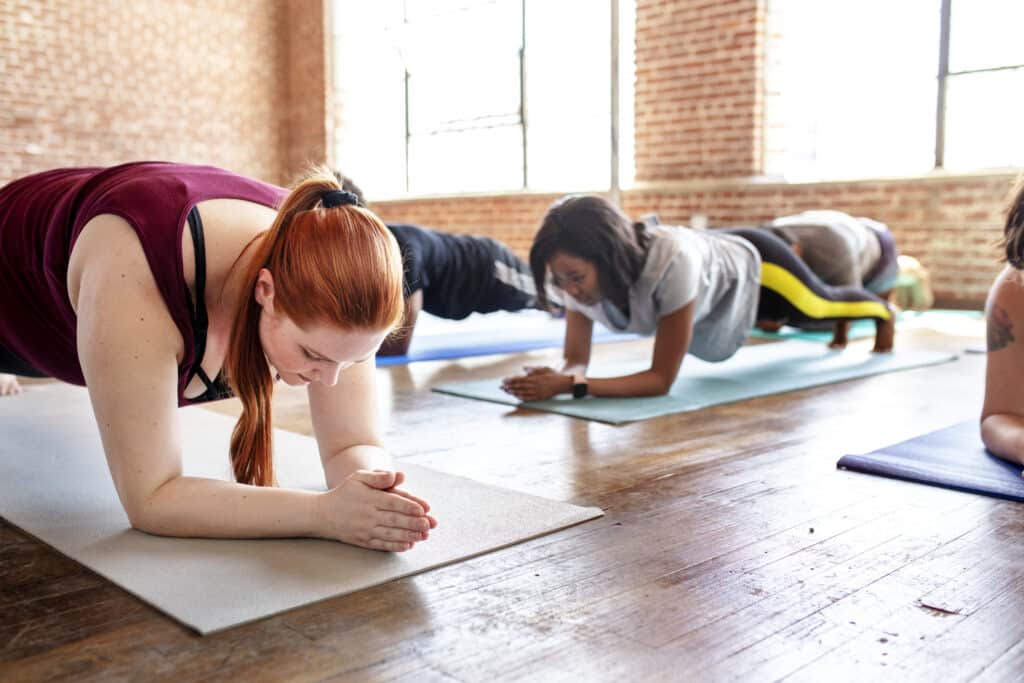 group of sporty people practicing the elbow plank