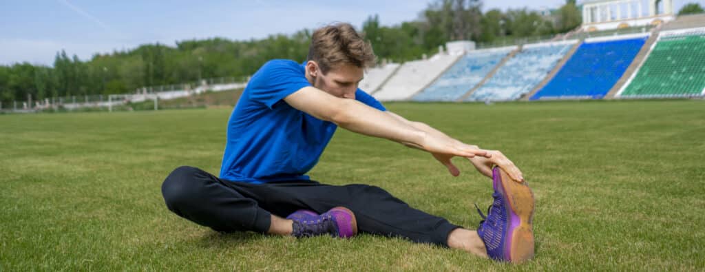 sportsman doing static stretch exercises on the stadium before summer practices