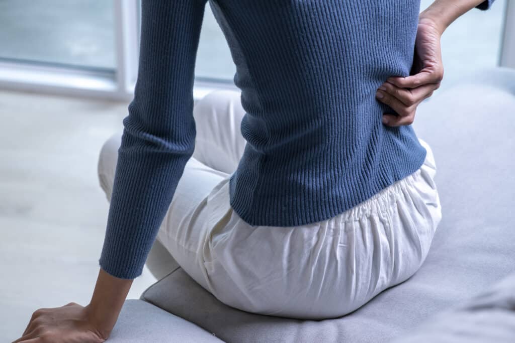 woman suffering from back ache on the sofa. female with back pain when sitting.