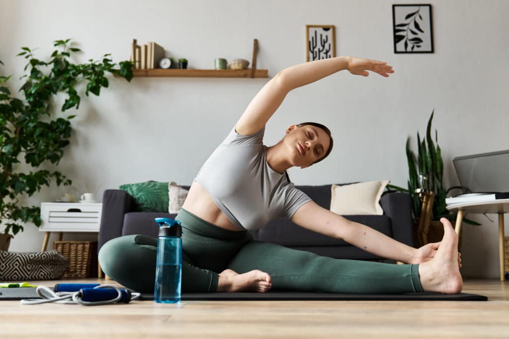 a young woman in a crop top and leggings uses static stretch method gracefully during her at home workout routine.