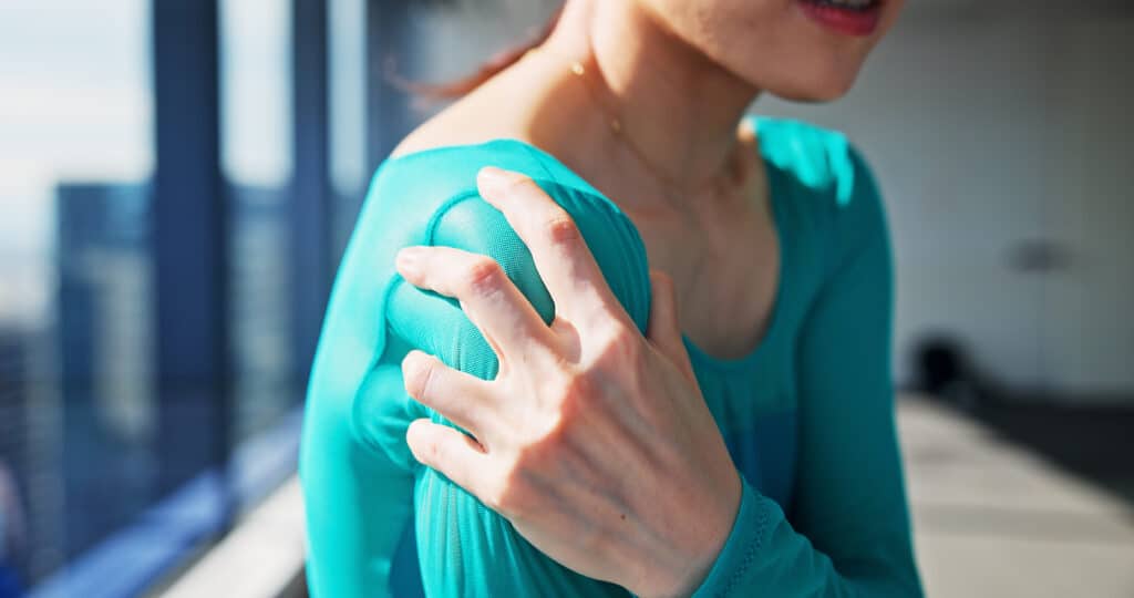 woman grasps shoulder with concerned look indoors 2026 03 25 02 16 14 utc