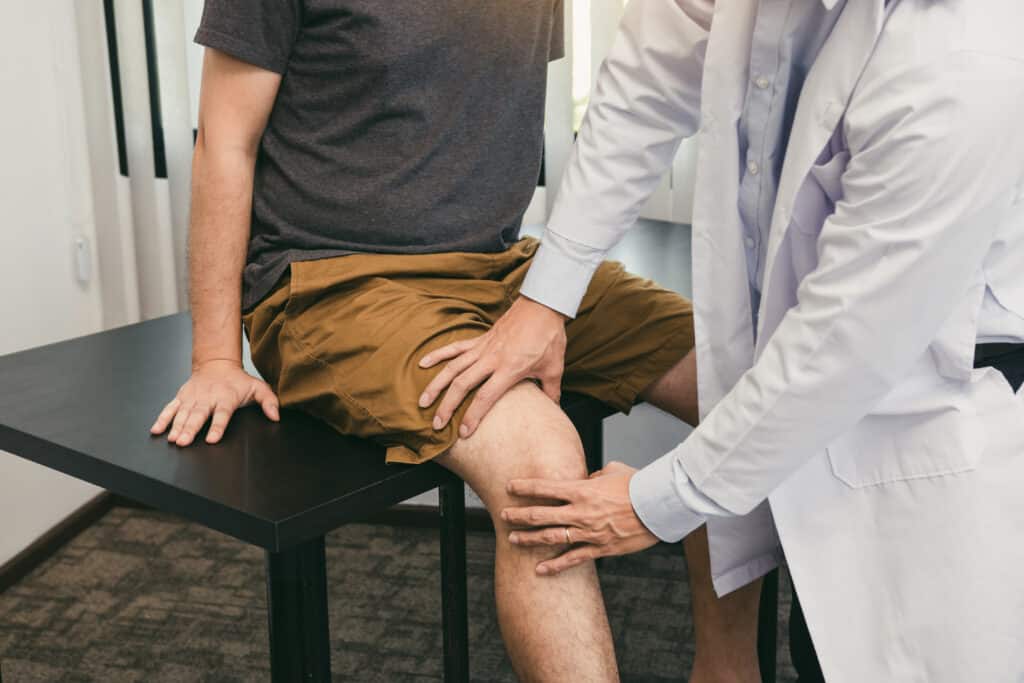 provider examining a swollen knee and comparing it with the other leg