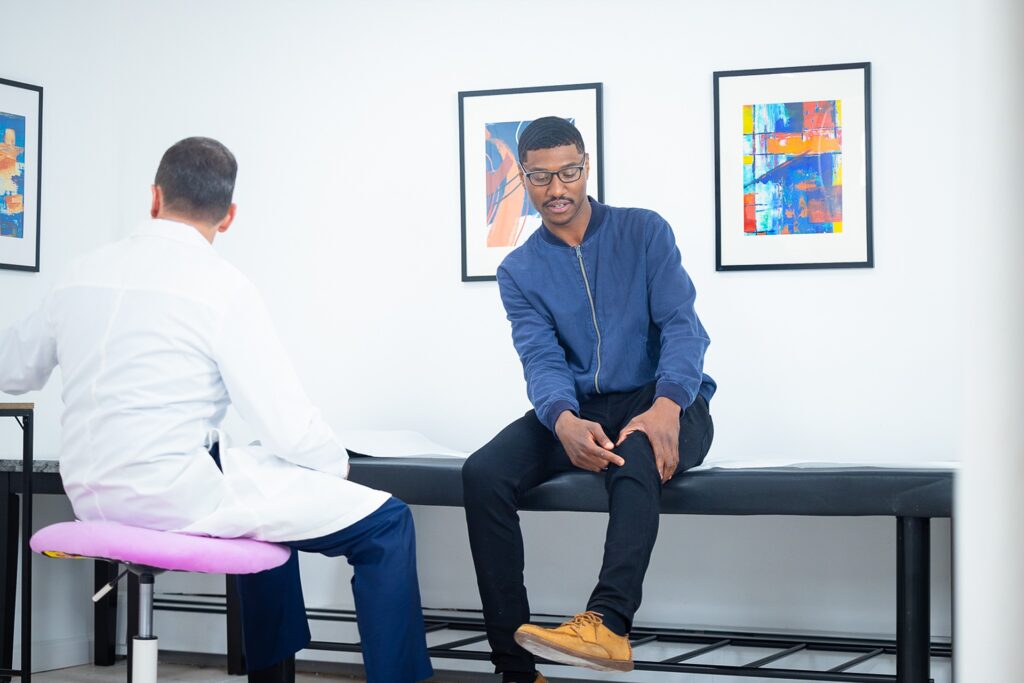 Patient pointing to pain around the kneecap during an orthopaedic knee exam